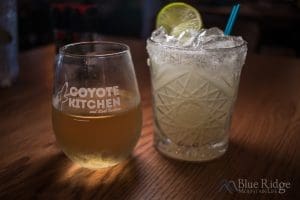 Close up of a glass of Chardonnay Wine, and a Margarita, garnished with a lime.
