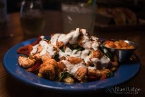 Close up of the Phoenix Bowl at Coyote Kitchen.  The bowl is blue, and full of bite sized chicken on top of rice and other vegatables, and drizzled with a white cream sauce.