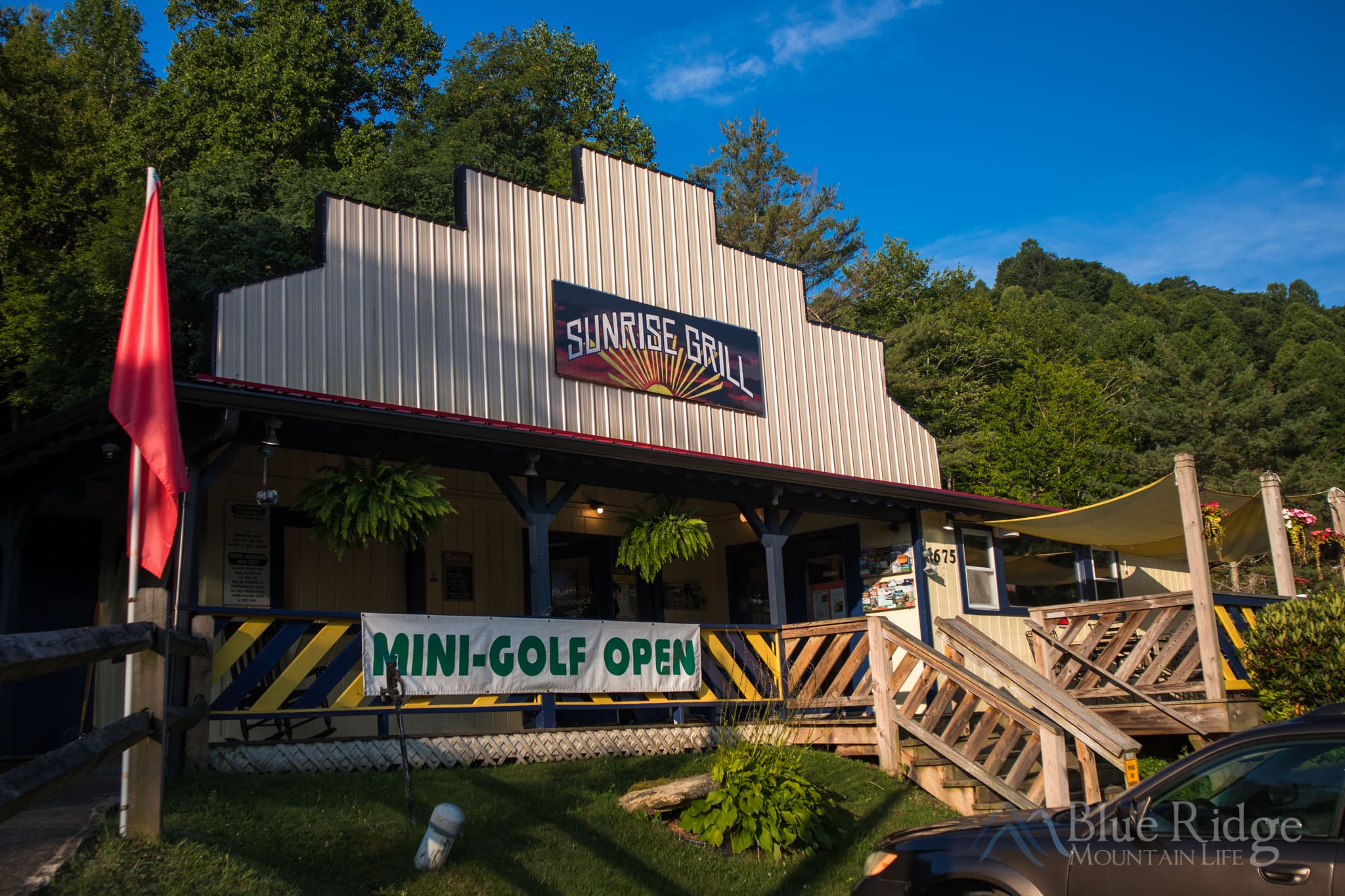 Sunrise Grill Boone NC Front Entrance to Sunrise Grill, with their sign, front deck area, and trees and blue skies behind the building.
