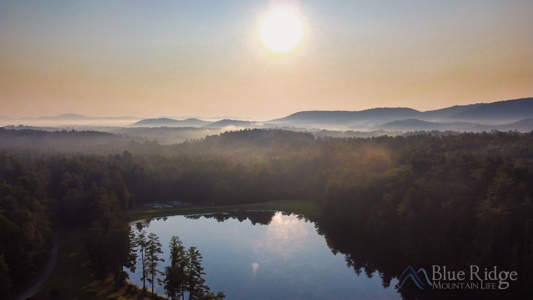 Kanuga in Hendersonville NC Sun rising in the morning over Lake Kanuga surrounded by mountains and forest.