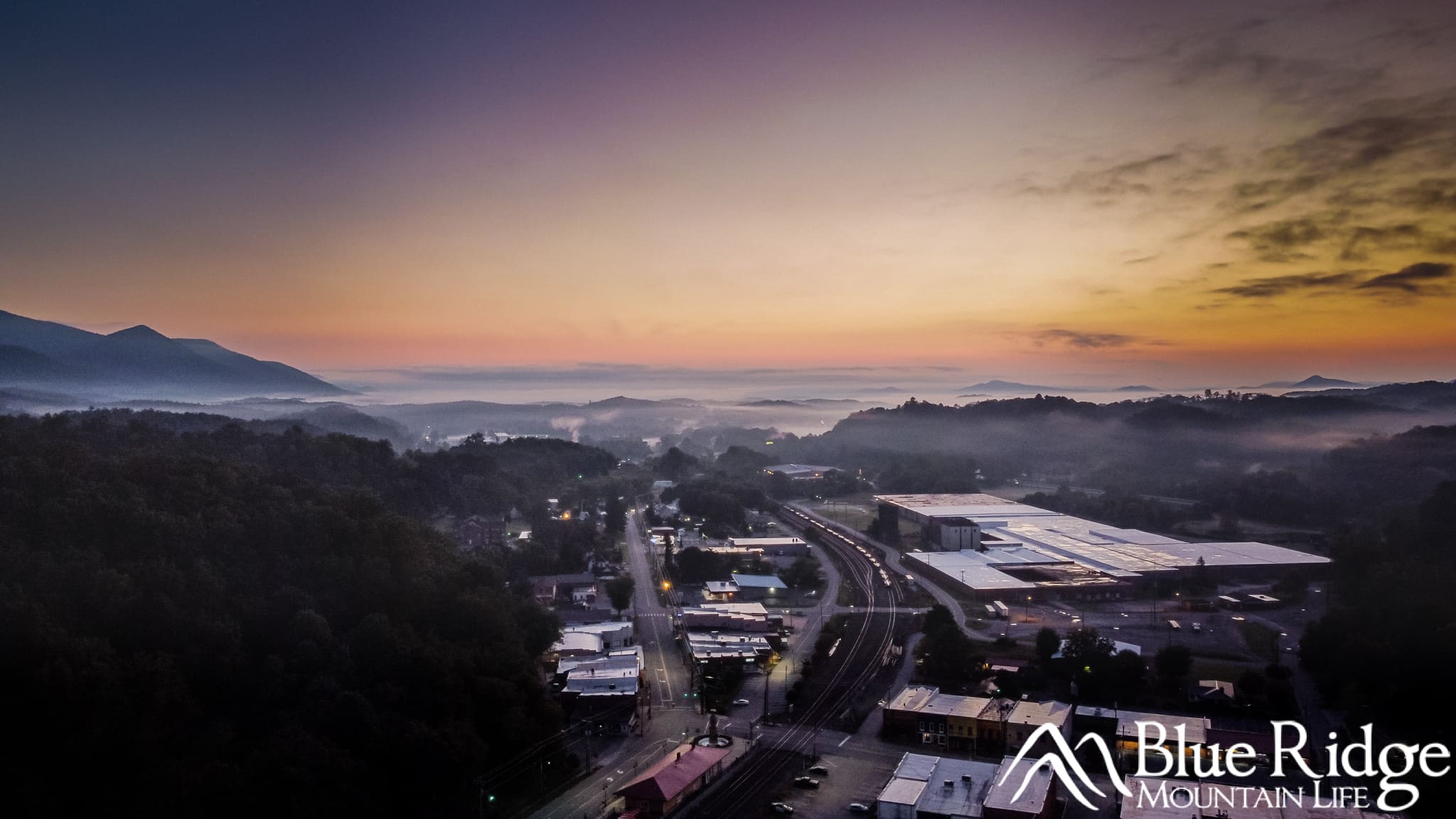 Aerial view of Old Fort, NC Early morning aerial photo of downtown Old Fort NC, showing the buildings surrounded by fog, and a beautiful orange sunrise in the distance over the purple/blue mountains.