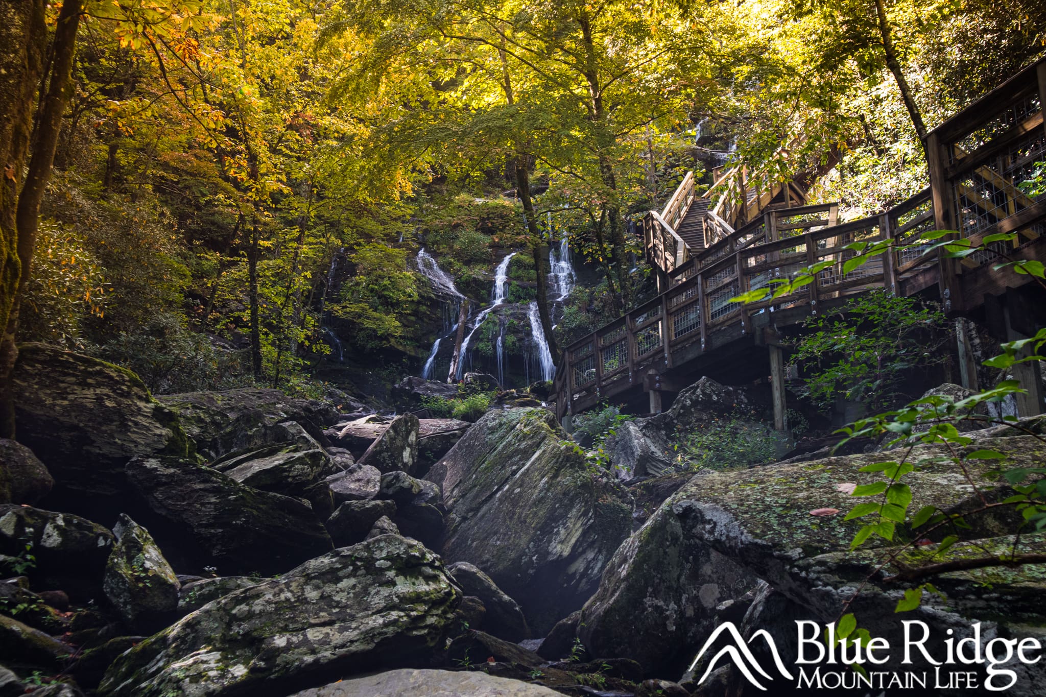 Catawba Falls near Old Fort NC Photo showing Catawba Falls in the distance, with the the wooden observation decking on the right side, rocks in the lower portion and trees surrounding the falls with early yellow fall color.