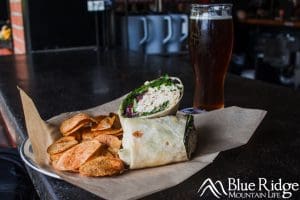 Turkey Salad wrap, cut in half showing the turkey salad, lettuce and tomato inside a flour wrap with chips.  