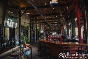 Interior photo of the bar area with a unique tap made from piping.  The photo shows the large ceilings with a modern and industrial look