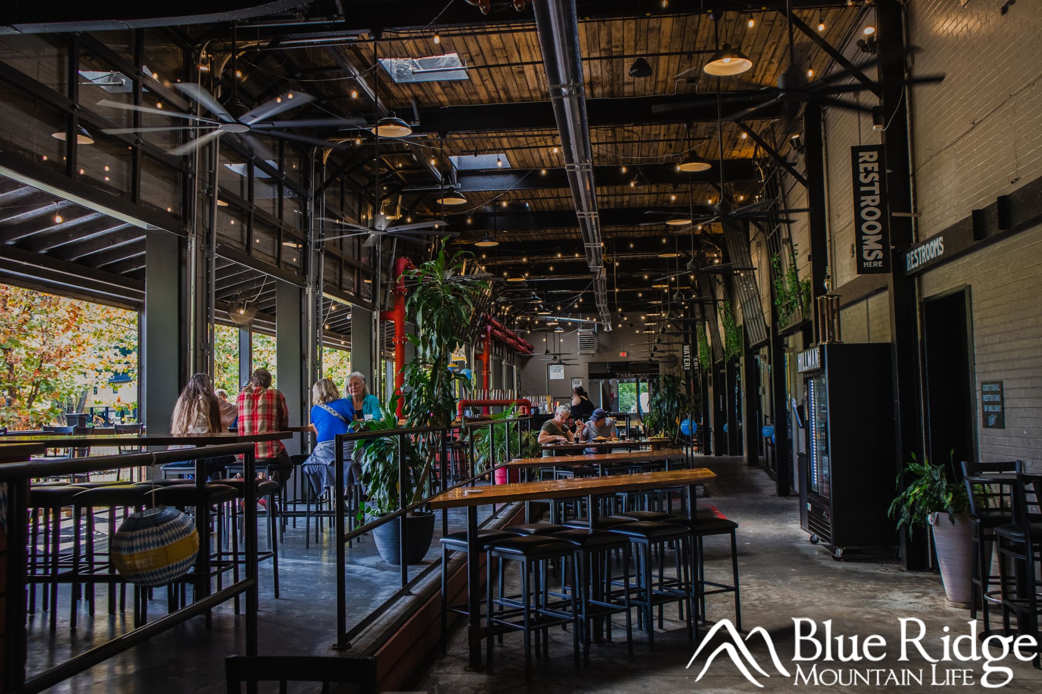 HIllman Beer Old Fort NC Interior of Hillman Beer in Old Fort NC showing the open atmosphere, tall ceilings. Customers are sitting at tables enjoying the food and beer.