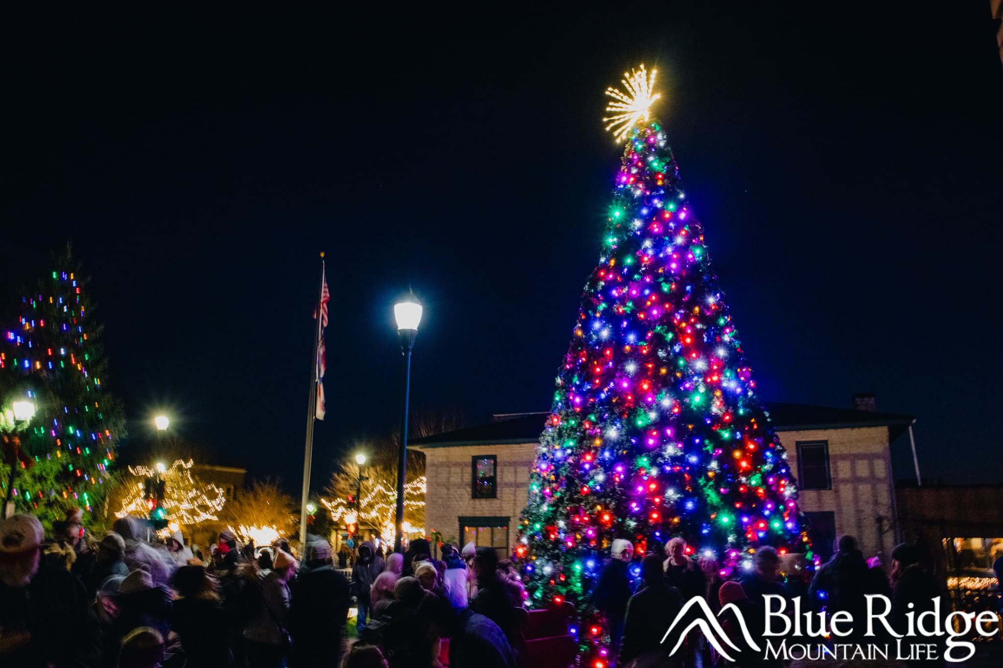 Christmas Tree Lighting in Hendersonville NC Glowing multicolor lights on a large Christmas tree with downtown Hendersonville in the background at night.