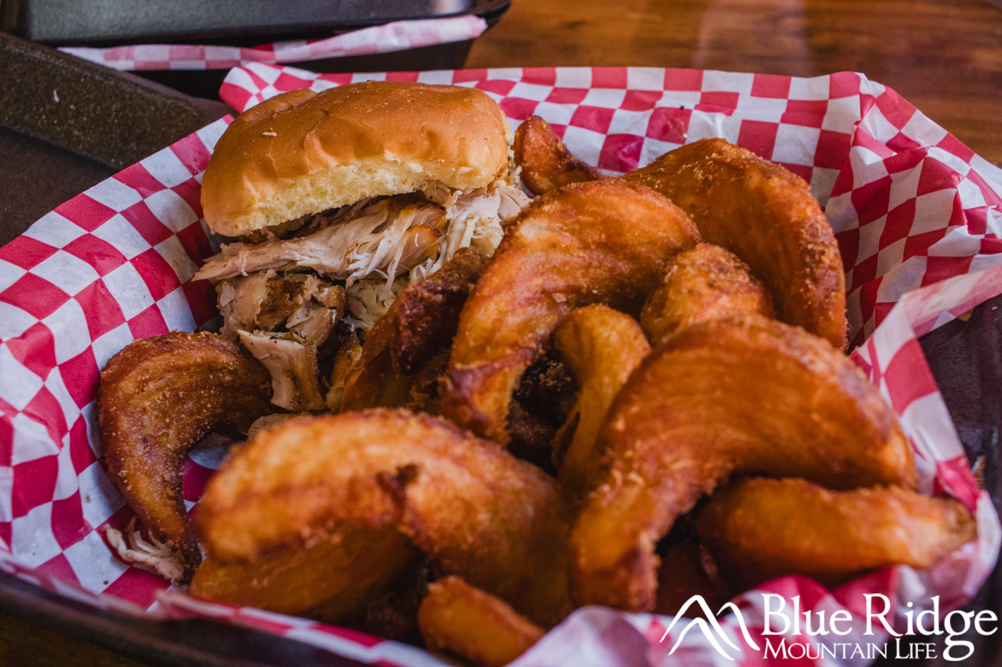 BBQ at Smoke A'lil Smoke BBQ Photo of a platter with checkered paper inside, holding a BBQ sandwich and fries.