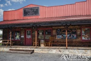 Photo of the front of Copper Creek Distillery Marion NC.  It resembles an old west building with a front porch