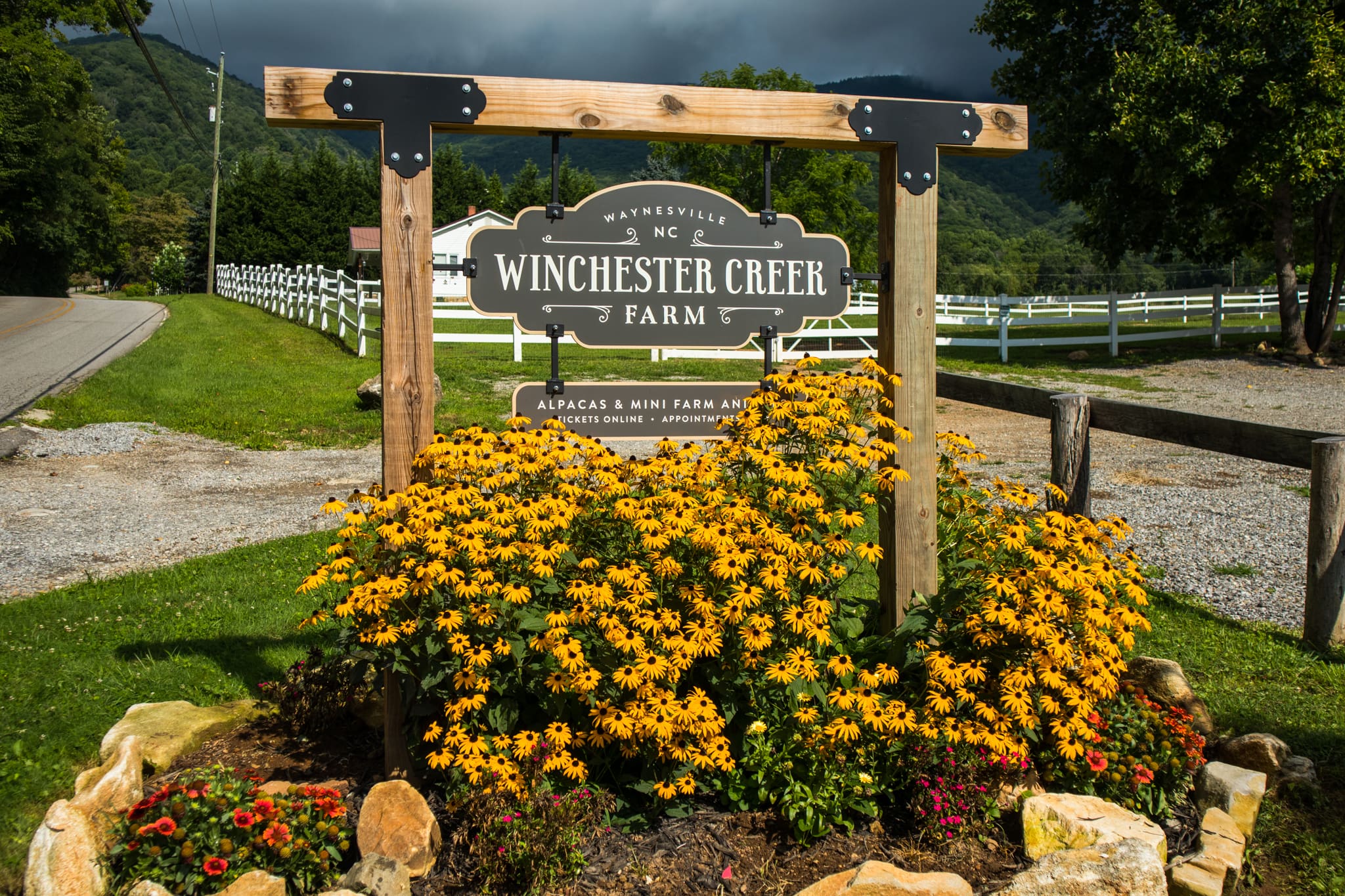 Winchester Creek Farms Waynesville NC Photo of Winchester Creek Farms entry sign, made of wood with yellow flowers around the sign.