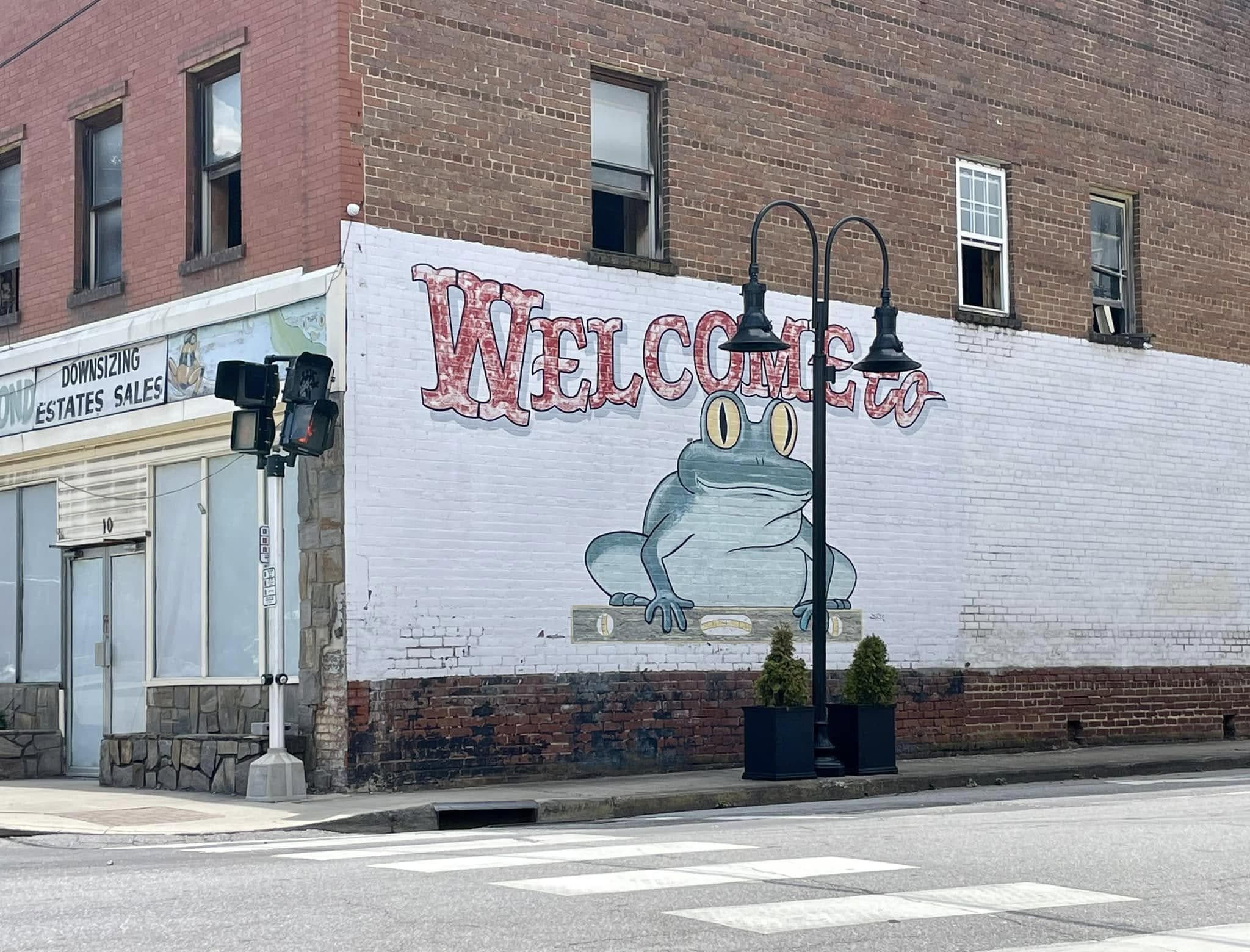 Frog Level in Waynesville NC Photo take at Frog Level in Waynesville NC shows the corner of a building, with a large white section, with a large green pained frog on it saying "Welcome"