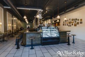 Photo of he interior of Waynesville Main Street Diner showing the while tile floor, front showcase full of deserts, and tables around the restaurant.